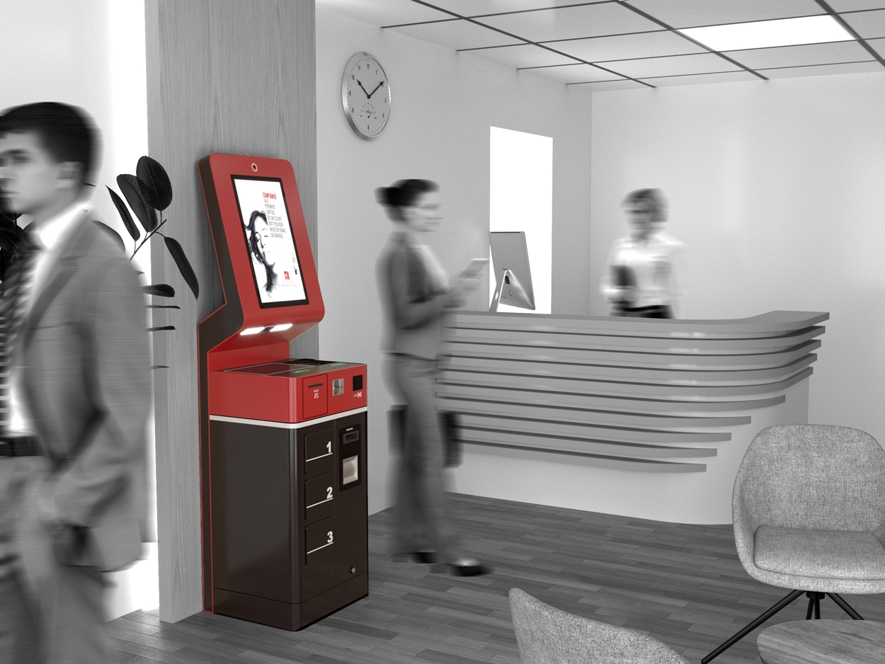 Un kiosque libre-service rouge et marron se trouve près d'un bureau de réception dans un hall de bureau moderne avec des personnes qui marchent et interagissent.